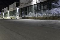 a big building with an empty parking lot at night time, on which cars are parked