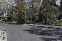 a street view of the street in front of a house with trees and bushes in front