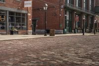 the sidewalk is lined with brick bricks, street signs and buildings in the city of a town