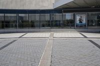 a person sitting at the bench in front of a mall that is empty of people