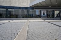 a person sitting at the bench in front of a mall that is empty of people