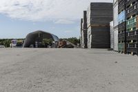 large wooden crates sitting in the middle of a parking lot near an airplane hangar with other equipment