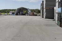 large wooden crates sitting in the middle of a parking lot near an airplane hangar with other equipment