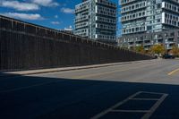 two tall buildings in a city, one behind the fence is a large street with yellow lines