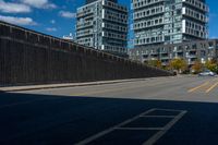 two tall buildings in a city, one behind the fence is a large street with yellow lines