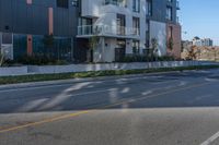 an apartment building sits next to the street corner, with a long side walk on one side