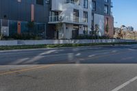 an apartment building sits next to the street corner, with a long side walk on one side