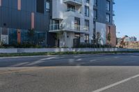 an apartment building sits next to the street corner, with a long side walk on one side