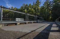 a concrete walkway through the woods in a park setting, in sunlight with blue sky