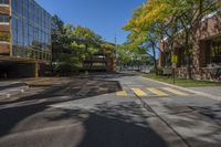 two tall buildings on both sides of a tree lined road with parked cars on it