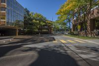 two tall buildings on both sides of a tree lined road with parked cars on it