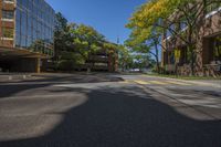 two tall buildings on both sides of a tree lined road with parked cars on it