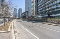 the empty road near the buildings in a city with cars parked on it's sides