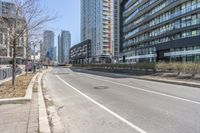 the empty road near the buildings in a city with cars parked on it's sides