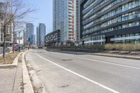 the empty road near the buildings in a city with cars parked on it's sides