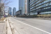 the empty road near the buildings in a city with cars parked on it's sides