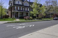 a paved city street with houses behind the curb with an arrow on the sidewalk and bike lanes