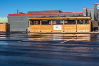 the car park with a wooden shelter is reflected in the wet street and parking lot