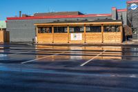 the car park with a wooden shelter is reflected in the wet street and parking lot