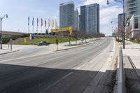 an empty street with tall buildings on each side of it, along with other tall buildings in the distance