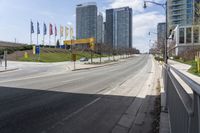 an empty street with tall buildings on each side of it, along with other tall buildings in the distance