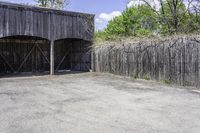 the view from behind the garage looking back at the inside of a barn with an outside entrance and grass, a fence, and trees behind which stands behind them are several gates