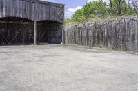 the view from behind the garage looking back at the inside of a barn with an outside entrance and grass, a fence, and trees behind which stands behind them are several gates