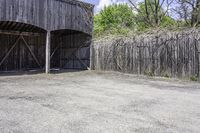 the view from behind the garage looking back at the inside of a barn with an outside entrance and grass, a fence, and trees behind which stands behind them are several gates