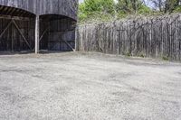 the view from behind the garage looking back at the inside of a barn with an outside entrance and grass, a fence, and trees behind which stands behind them are several gates