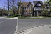 two houses in a residential area with one large building on the other side and trees in the street