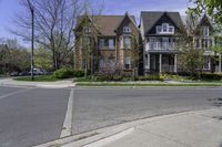 two houses in a residential area with one large building on the other side and trees in the street