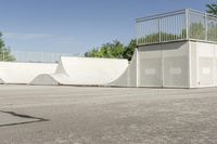 an empty parking lot with a skate board ramp to it and some trees in the background