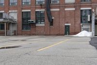 the empty parking lot has only snow on the ground in front of an old brick factory