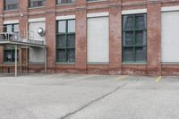 the empty parking lot has only snow on the ground in front of an old brick factory