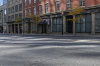 the empty street has cars on it and trees on either side of the road with buildings