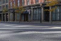 the empty street has cars on it and trees on either side of the road with buildings