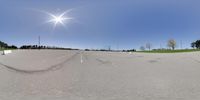 an empty parking lot with the sun shining overhead a car is parked along with a curb