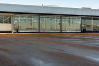 an empty parking lot is shown on a sunny day at the airport, in front of an aircraft hangar