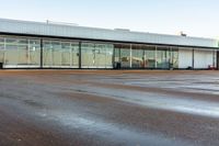 an empty parking lot is shown on a sunny day at the airport, in front of an aircraft hangar