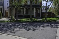 a big two story house on a street corner with a sidewalk and lawn area in front