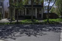 a big two story house on a street corner with a sidewalk and lawn area in front