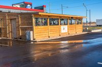 a wooden shop front with a red roof in the middle of the street and it's water reflecting on the road