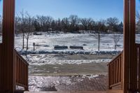 looking out into a large open gated park area in winter time with lots of snow on the ground