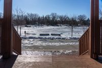 looking out into a large open gated park area in winter time with lots of snow on the ground