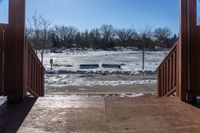 looking out into a large open gated park area in winter time with lots of snow on the ground