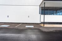 a parking lot with white walls and parking spaces in front of it and a light post outside