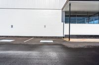 a parking lot with white walls and parking spaces in front of it and a light post outside