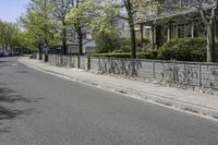 a street is lined with concrete fences and trees and buildings are behind it on both sides of the road