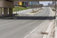 an empty street below a bridge over the highway, where there are benches and signs to the right