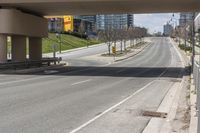 an empty street below a bridge over the highway, where there are benches and signs to the right